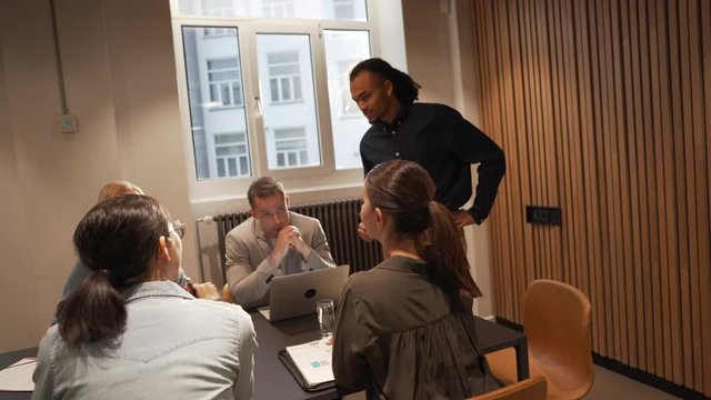 Young businessman talking with a group of diverse colleagues during a meeting in an office boardroom