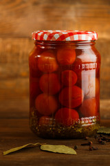 Jars of pickled homemade pickled cherry tomatoes on a wooden table.