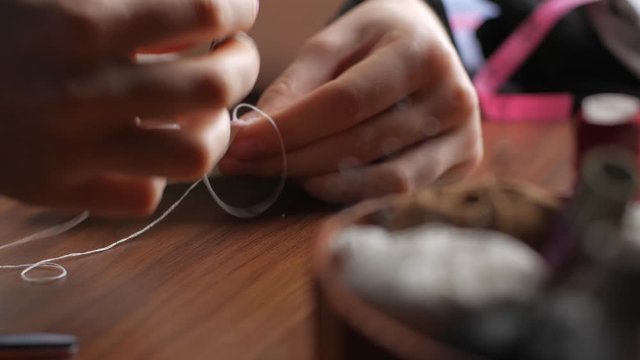 Hands of a young woman in a sewing thimble from white cotton fabric at night in the house. Making your own reusable protection masks. Close-up view of a woman's hands.
