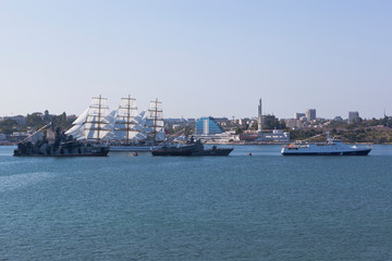 Fototapeta premium Sailboat Khersones walks along the parade of military ships at the parade on Navy Day in Sevastopol Bay, Crimea