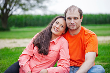 Fototapeta premium Portrait of happy young couple sitting together on grass