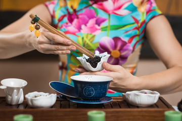 Tea ceremony. The girl makes a tea drink. Translation of the text on the cup Blessing.