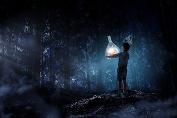 Boy holding glass flask with landscape inside it