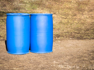 Two blue plastic barrels stand on ground. The concept of safe storage of liquids