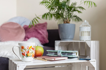Cozy living space for working from home - coffe mug, planners, apple, palm and pillows