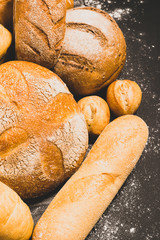 Fresh baked bread with a golden crust, loaf, buns, white, rye on a rustic wooden background with sil rustic. Flat layout
