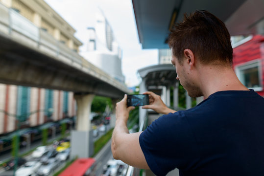 Closeup rear view of young man taking picture of the city using phone