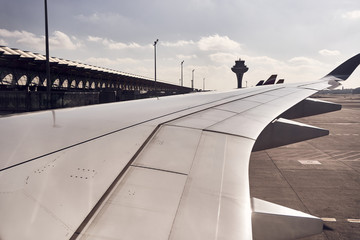 View of the plane's wing with the control tower's background, in the port of madrid.