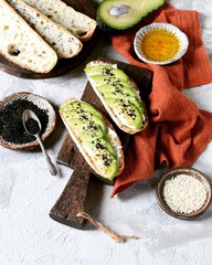Sandwich with avocado, curd cheese, chia seeds and sesame seeds on a gray background