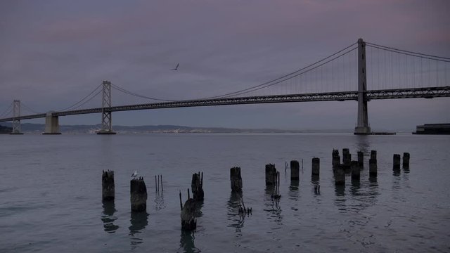 sunset shot of old pylons and the bay bridge at san francisco in northern california, usa
