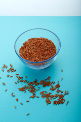 Glass jar with brown rice on a blue background.