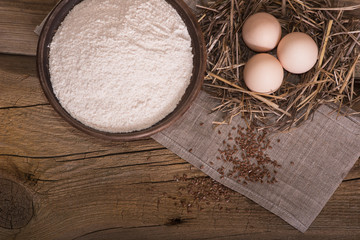 Chicken eggs wrapped in straw on a table with flour