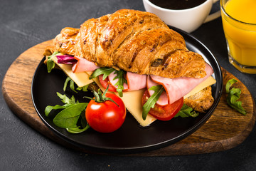 Croissant sandwich on black table.