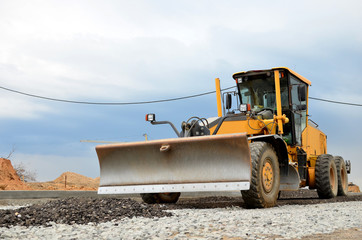 Obraz na płótnie Canvas Сonstruction machine Motor Grader at a construction site level the ground and gravel stones for the construction of a new asphalt road. Road construction equipment