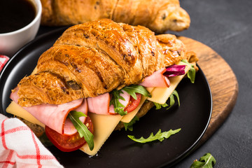 Croissant sandwich on black table.