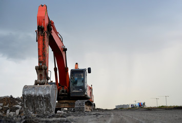 A heavy excavator in a working at granite quarry unloads old concrete stones for crushing and...