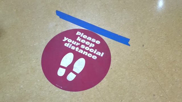 Sign on floor of store stating Please keep your distance with lines marking physical distancing of six feet between customers during COVID nineteen Coronavirus global pandemic