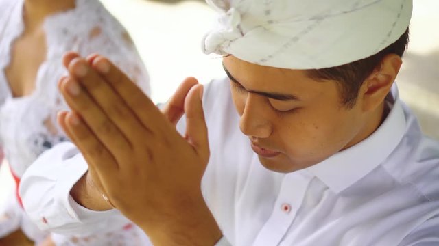 Man praying with putting hands to forehead head. Balinese hindu man in Bali.