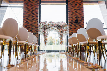 Area for the wedding ceremony, a wedding arch decorated with fresh flowers in beige and gold...