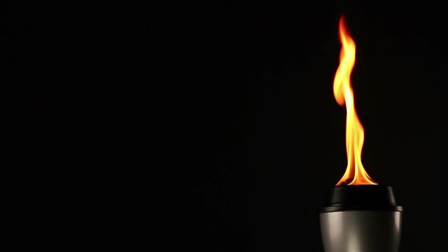 Flaming Torch on a Black Background with flames burning. Copyspace. Tracking Shot. Stock Video Clip Footage