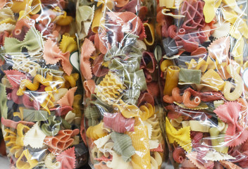 Colored italian pasta. Raw pasta in transparent packages