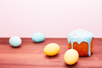 Turquoise and yellow Easter eggs on a pink background with Easter cake in glaze