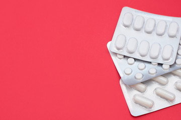 Pills blisters on red background with a copy space