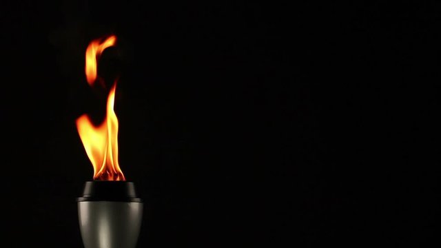 Flaming Torch on a Black Background with flames burning. Copyspace. Stock Video Clip Footage