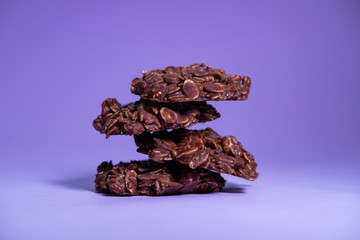 Oatmeal cookies with peanut butter and chocolate powder on purple background. Healthy and no-bake snack.