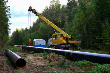 Crane lowers a section of pipe into a trench. Construction of gas pipeline to new LNG plant....
