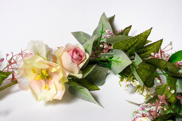 Artificial flowers on a white background. Pink and yellow roses.