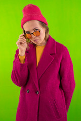 Young elegant woman in trendy purple coat. Fashion autumn lookbook. Model woman in sunglasses. In the studio on a green background.