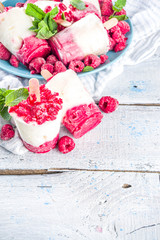 Sweet and tasty diet summer dessert. Homemade raspberry yogurt popsicle with fresh raspberries and mint. Healthy ice cream recipe. Wooden white background copy space