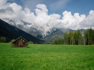 Fototapeta na wymiar Wiese mit Hütte vor Berglandschaft in Tirol