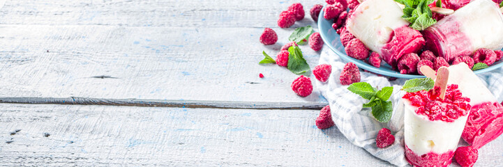 Sweet and tasty diet summer dessert. Homemade raspberry yogurt popsicle with fresh raspberries and mint. Healthy ice cream recipe. Wooden white background copy space