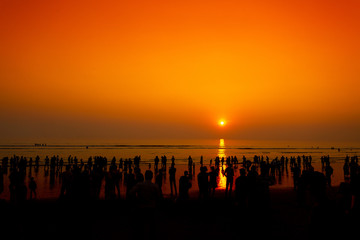 Crowd of silhouette people walking on the longest beach during sunset at Chattogram.