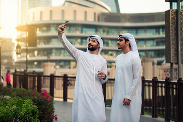 two Arab young men taking selfie in Dubai streets 