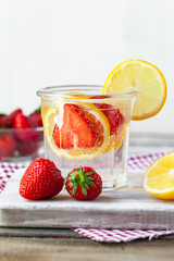 Refreshing homemade lemonade with fresh strawberry, lemon and ice. Healthy cold drink, low calories. Tasty cool summer beverage. Wooden white background, two glasses. Copy space for text