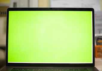 Laptop on table with green screen.