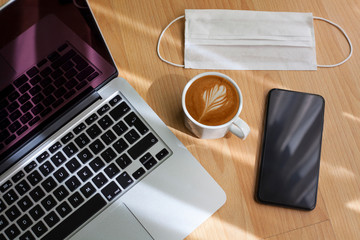 laptop, mobile phone, coffee and disposable mask is on the work desk, working from home in quarantine days. Studying, staying at home. Study, work desk. Online education. Home office.