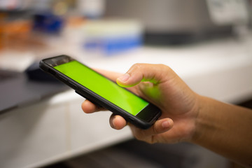 Hand holding smart phone green screen.