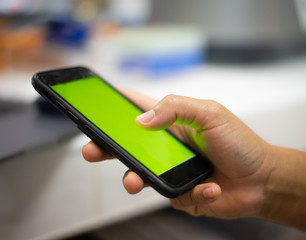 Hand holding smart phone green screen.