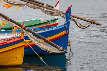 Fototapeta na wymiar Detail of some multi colored wooden boats on the sea in a town of France
