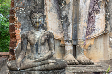 Fototapeta na wymiar Two buddha sculptures, one sitting and the other standing, in Sukhothai, Thailand
