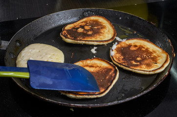  Pancakes are fried in a pan on an induction stove