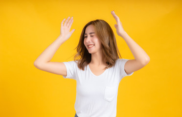 Portrait happy young asian woman dancing music celebrate fun enjoyment relaxation smiling positive emotion in white t-shirt, Yellow background isolated studio shot and copy space, party concept.