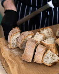Fresh baked bread being sliced by hand