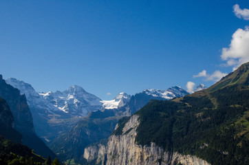 Picturesque Alpine village Wengen, Switzerland. Famous Lauterbrunnen and Staubbach Falls in background. Swiss Alps with snow on top. Switzerland in summer. Alpine landscape