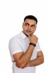 Studio shot of young handsome Indian man thinking isolated against white background