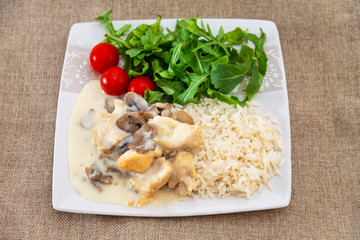 Pieces of chicken fillet cooked in a cream sauce with mushrooms and lemon juice, served with rice.